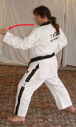 2) Turn 90° to the left towards B, perform a middle section inner forearm block (middle block – knuckles down) with the left arm, hip-twisting into a left walking stance (bent front knee, straight back leg, heel on ground, weight 50/50, pivot on ball of left foot for hip twist )