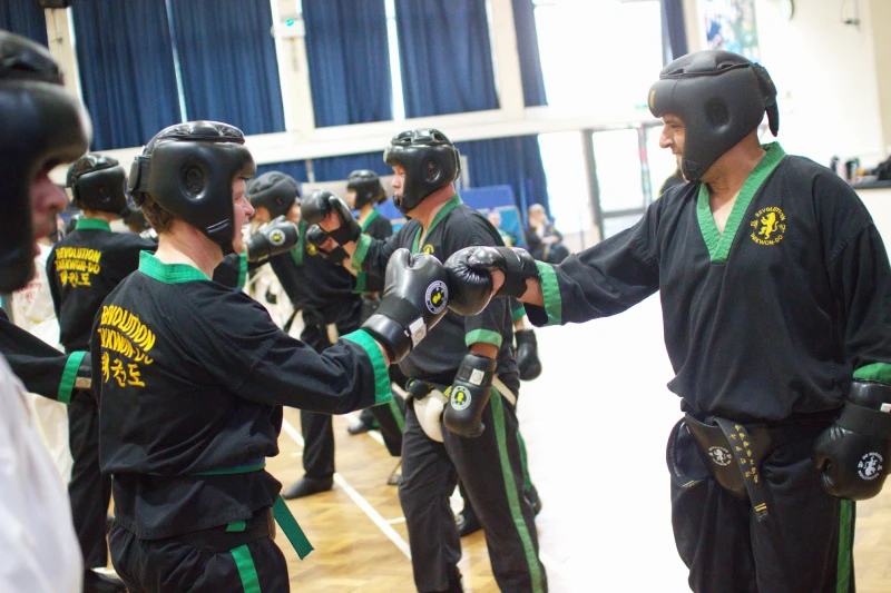 Students in full protective kit touch gloves in salute while smiling