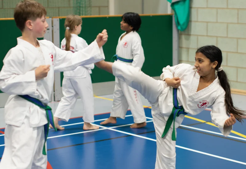 A young girl practices a high kick